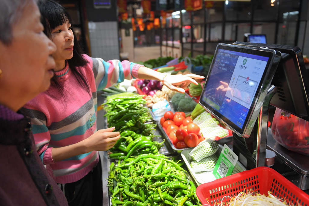 10月15日，今朝星市集智慧农贸市场的经营户在帮助市民查看菜品信息。