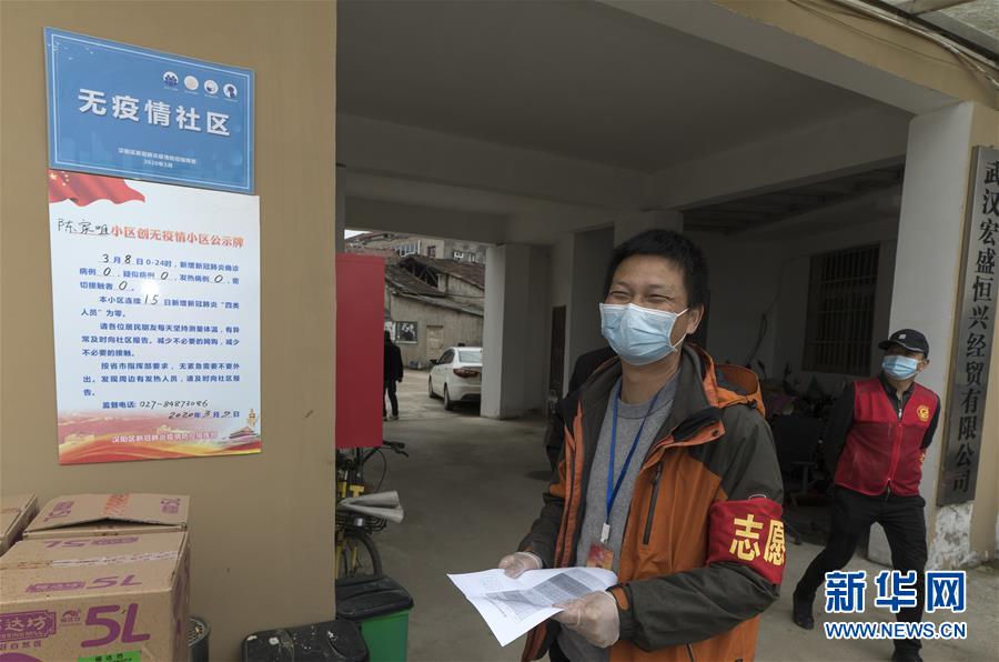 3月9日，汉阳区陈家咀社区书记陈伟在“无疫情社区”的牌子旁开心地笑。