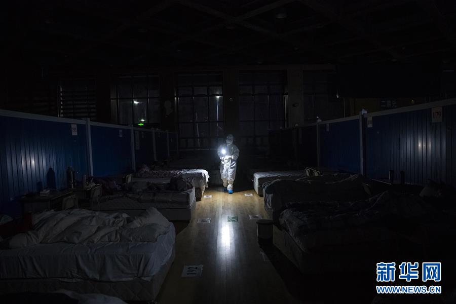 3月9日晚，在位于武汉市洪山体育馆的武昌方舱医院，江西支援湖北医疗队队员胡佩在熄灯后巡视，查看患者休息情况。