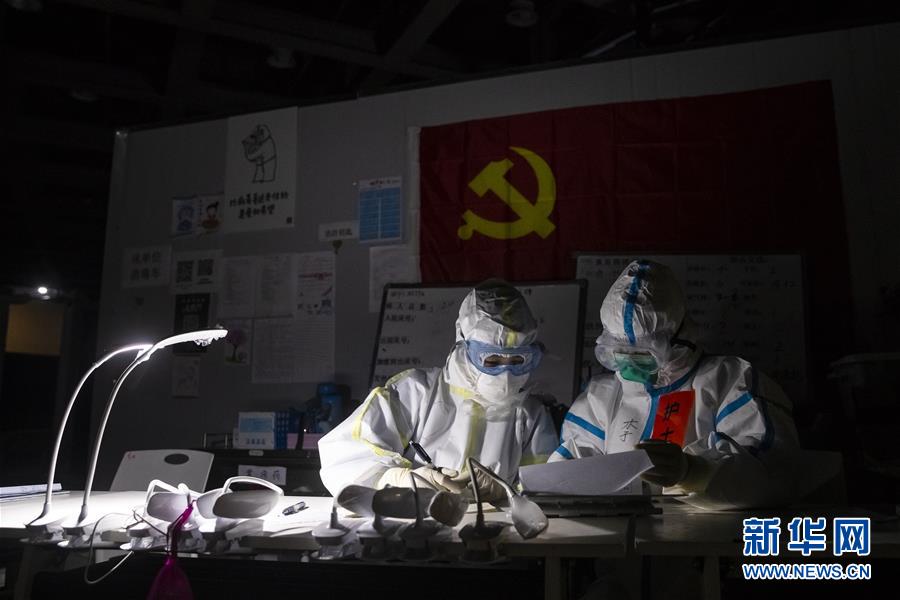 3月9日晚，在位于武汉市洪山体育馆的武昌方舱医院，江西支援湖北医疗队队员胡佩（左）和护士李政嫱在护士站工作。