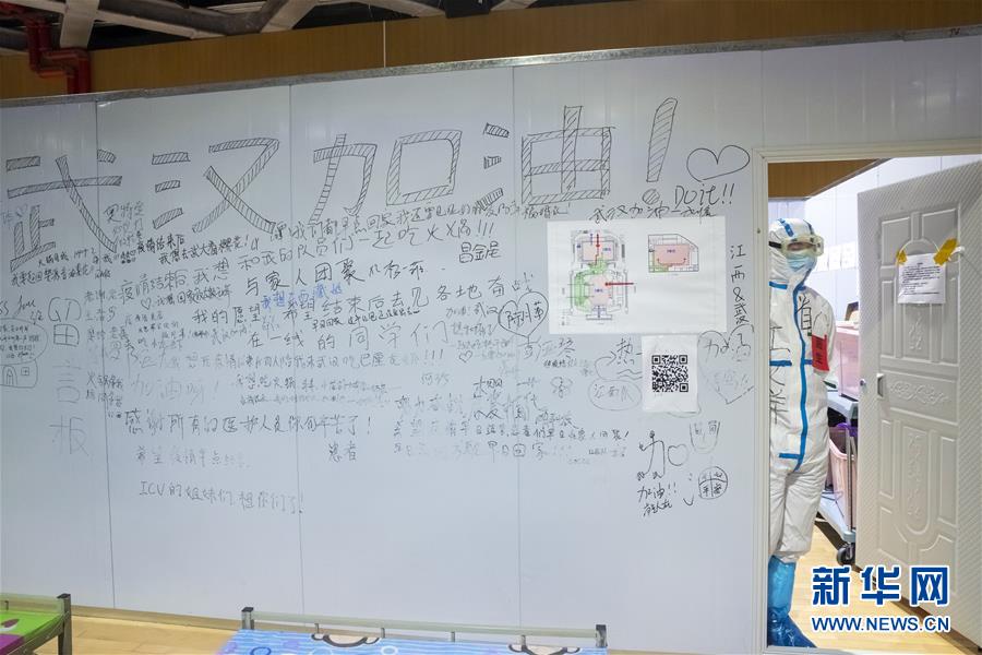 3月9日晚，在武汉市洪山体育馆武昌方舱医院，医生江文洋站在一片留言板旁看着方舱里的“战友”和“病友”们。