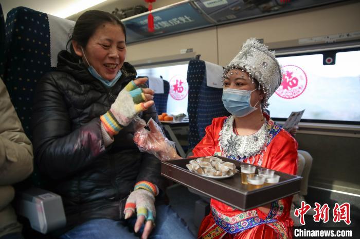图为穿着少数民族服装的列车员郑燕将贵州特色年货分发给旅客品尝。　瞿宏伦 摄