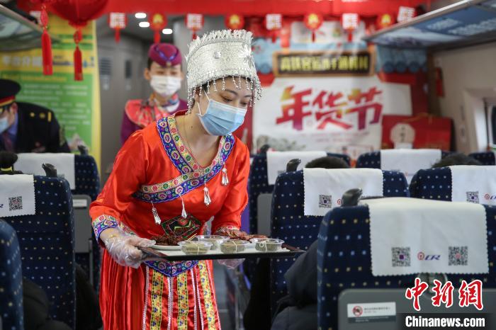 图为穿着少数民族服装的列车员郑燕在推介贵州特色年货。　瞿宏伦 摄