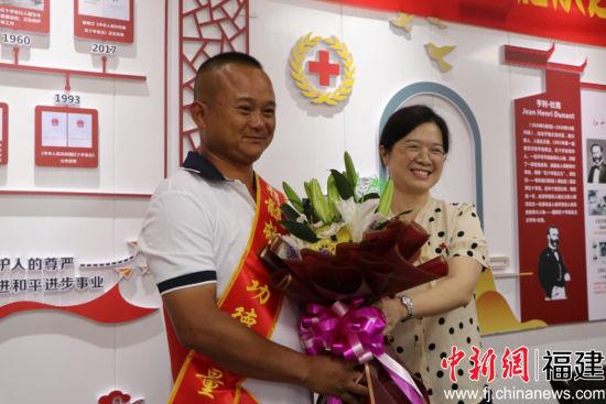 晋江市红十字会专职副会长卢奕珠代表市红十字会向造血干细胞捐赠者林时勤（左）献花表达敬意。牛效礼摄。