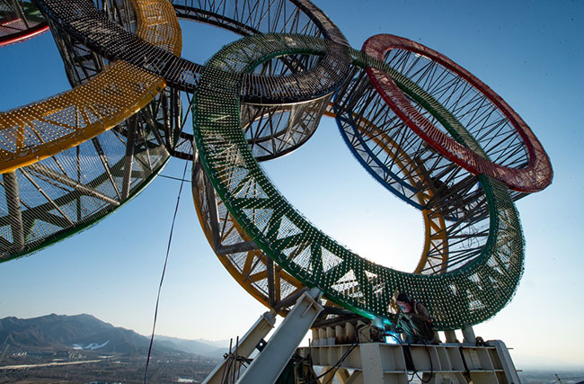 1月11日，工人们在“海陀塔”塔顶的奥运五环标志下作业。