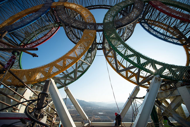 1月11日，工人们在“海陀塔”塔顶的奥运五环标志下作业。
