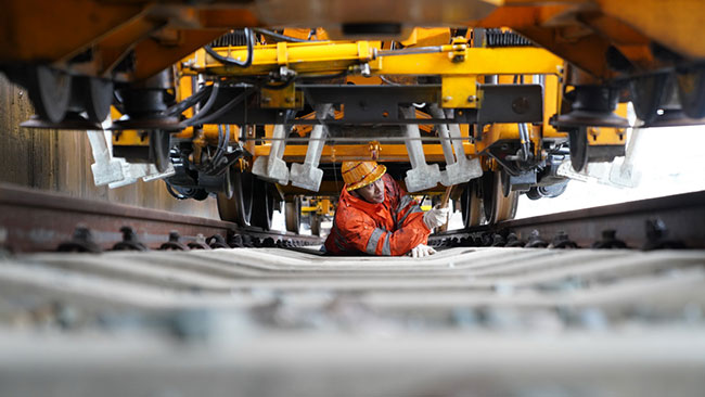 鹰潭工务机械段工作人员钻入车辆底部检查车辆设备（1月27日摄）。