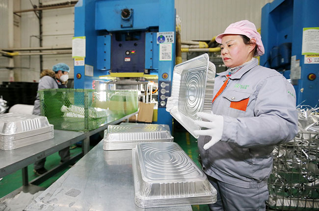 2月7日，工人在安徽省淮北市濉溪经济开发区一家铝箔餐盒加工企业生产车间忙碌。新华社发（万善朝摄）