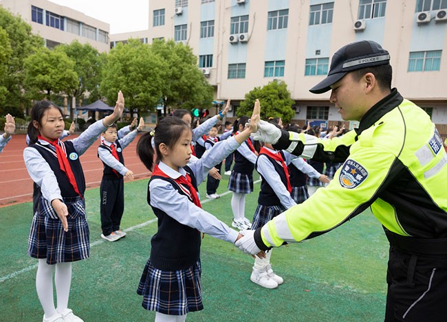 4月14日，浙江省诸暨市公安局的民警在浣纱小学指导学生学习交通指挥手势。新华社发（郭斌 摄）