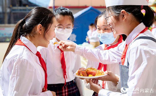 5月30日，内蒙古呼和浩特市玉泉区恒昌店巷小学学生在赛后品尝西红柿炒鸡蛋。丁根厚摄