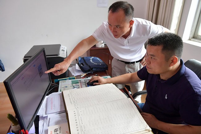 在江西省乐平市退役军人事务局，程雪清（左）在工作人员帮助下上网查找烈士资料（7月6日摄）。新华社记者 彭昭之 摄