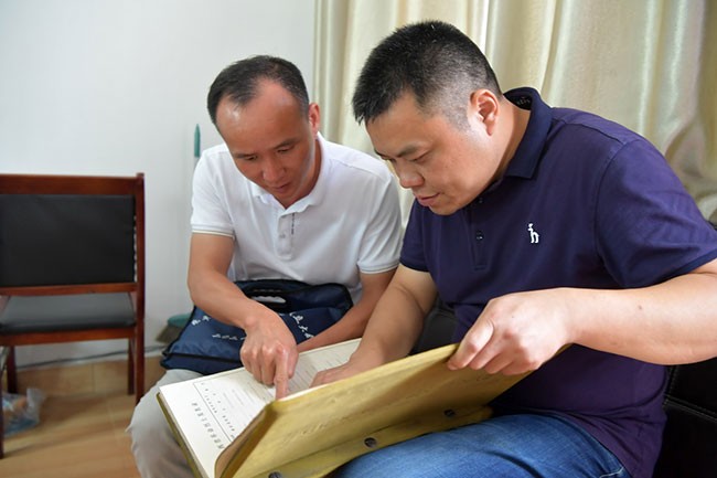 在江西省乐平市退役军人事务局，程雪清（左）在工作人员的帮助下，翻阅江西革命烈士英名录，查找他要寻找的烈士（7月6日摄）。新华社记者 彭昭之 摄