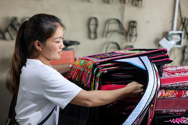 7月19日，30岁的杨丽在克度镇马鞍社区一刺绣厂内工作。杨丽家是“中国天眼”所在“大窝凼”内的12户居民之一。2009年，杨丽家搬迁至克度镇的移民安置点。如今，杨丽在克度镇马鞍社区一刺绣厂内担任管理工作。